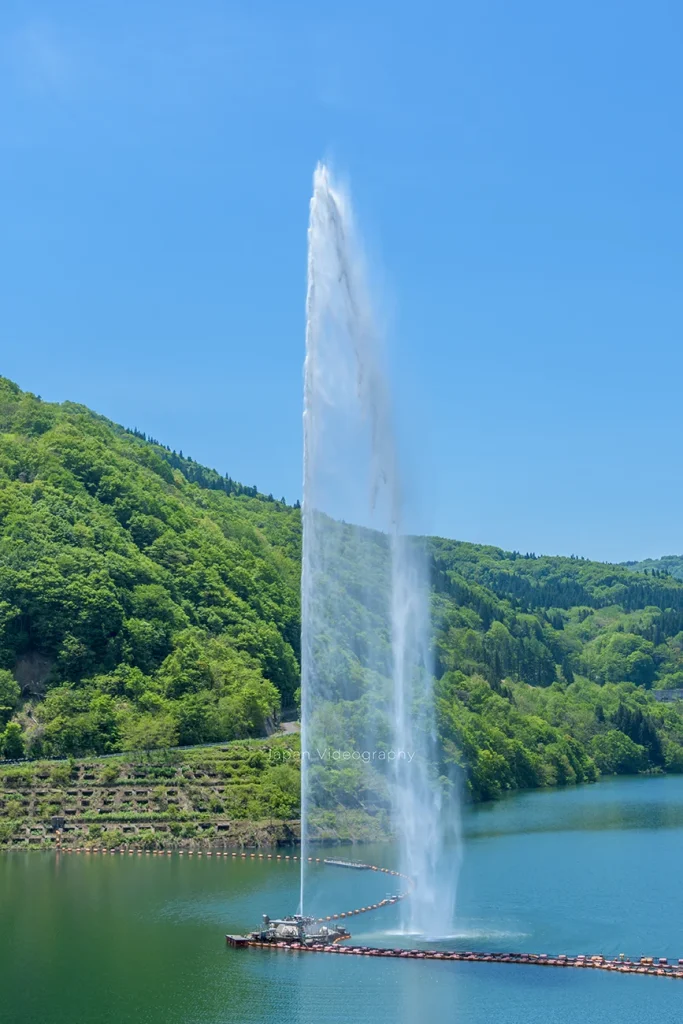 寒河江ダムにある月山湖大噴水が高く水柱を上げる画像